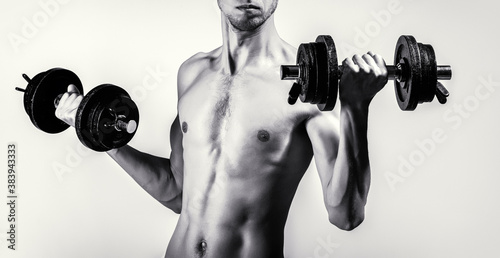 Skinny guy hold dumbbells up in hands. A thin man in sports with dumbbells. Weak man lift a weight, dumbbells, biceps, muscle, fitness. Nerd maleraising a dumbbell. Black and white