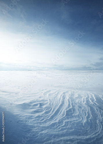 Panoramic view of the snow-covered field after a blizzard at sunset. Human tracks in a fresh snow. Ice desert. Dramatic cloudscape. Global warming theme. Lapland, Finland