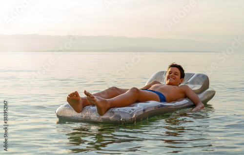 
Young boy lies on an inflatable mattress on the water