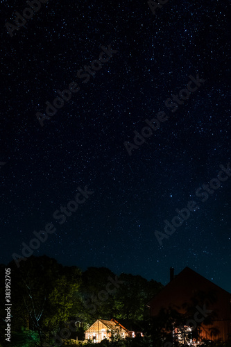 night sky with stars over an illuminated greenhouse in the swedish countryside © Per