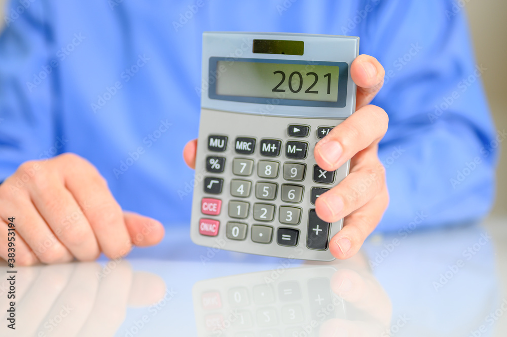 Geschäftsmann mit einem Taschenrechner und der Zahl 2021 Geschäftsmann mit einem Taschenrechner und der Zahl 2021