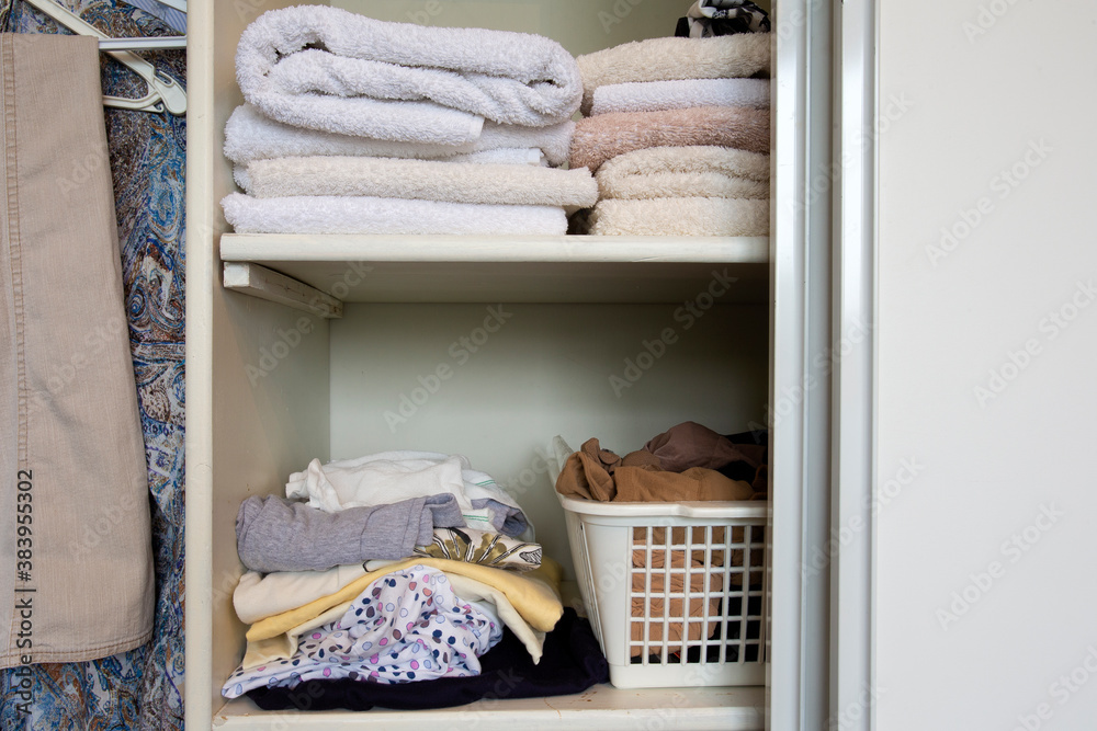 Full closet with clothes and Stack of towels in white wooden closet, organization and storage
