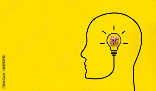 on a yellow background there is a half of a walnut. concept idea in the human brain - a light bulb is on