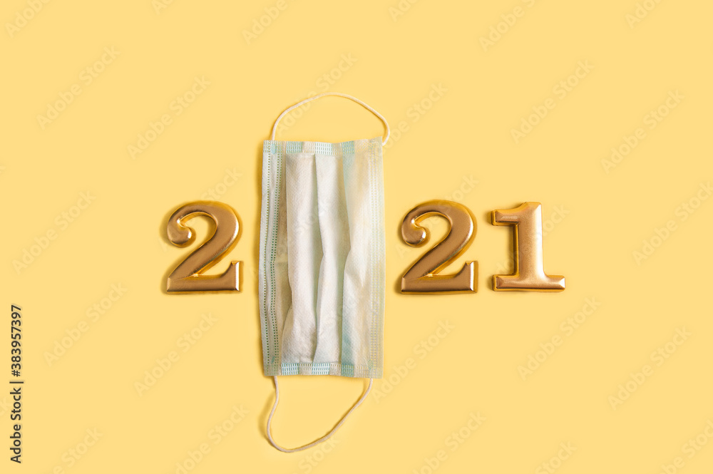 Happy New Year 2021. Numbers 2021 in gold and a medical mask on a yellow background. Covid 2019 and New Year lettering numbers. Happy New Year 2021. Numbers 2021 in gold and a medical mask on a yellow background. Covid 2019 and New Year lettering numbers.