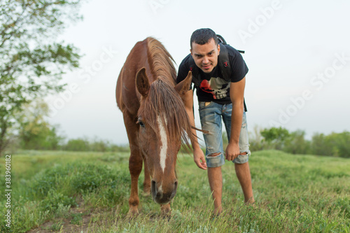 Guy with a horse in a green field. Communication with animals