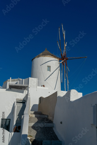 Famous traditional windmill in Oia town in Santorini island ,Greece. Greek landscape on a sunny day. Portrait format