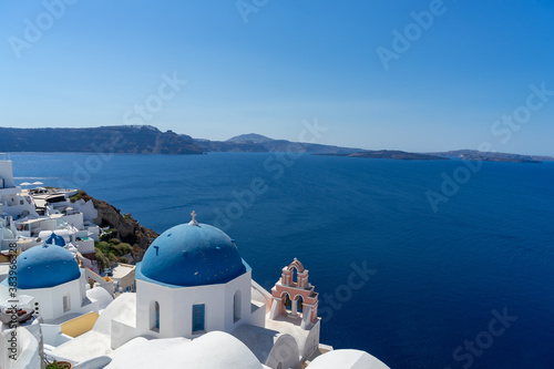Iconic view of Santorini, with typical blue dome church, sea and white facades. Detail of the roof of an orthodox church. Blue domed church along caldera edge in Oia, Santorini