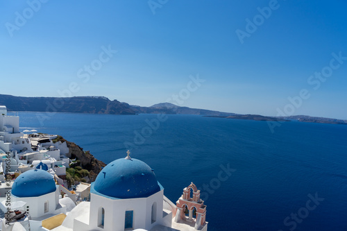 Iconic view of Santorini, with typical blue dome church, sea and white facades. Detail of the roof of an orthodox church. Blue domed church along caldera edge in Oia, Santorini