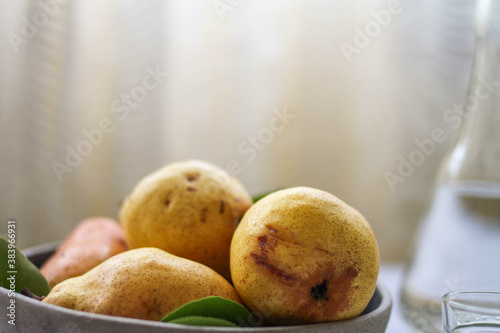 A bowl of fresh pears and a bottle of pear brandy.