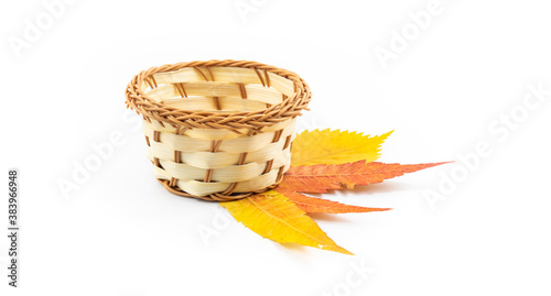 Beautiful wicker basket autumn composition with leaves on white isolated background