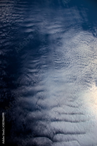 carpet formed by white cirrocumulus clouds with different textures, floating under a navy blue sky.