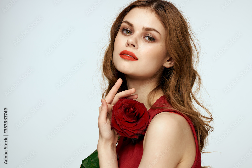 Beautiful woman in a red dress holds a rose in her hand a gift flowers decoration attractive look Beautiful woman in a red dress holds a rose in her hand a gift flowers decoration attractive look