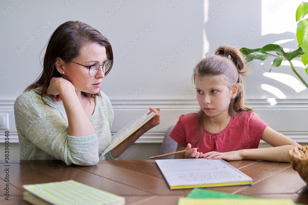 Mother and daughter child study together at home, sitting at table Mother and daughter child study together at home, sitting at table