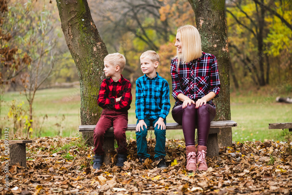 Mother with kids twins sit at bench