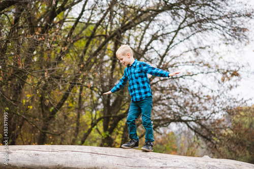Preteen kid balance on fallen tree trunk