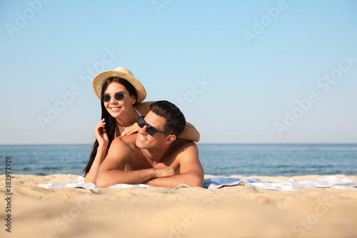 Happy couple resting on sunny beach. Space for text