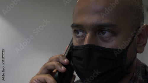 Adult Male Wearing Face Mask Talking On Mobile Phone Call. Locked Off , Close Up photo