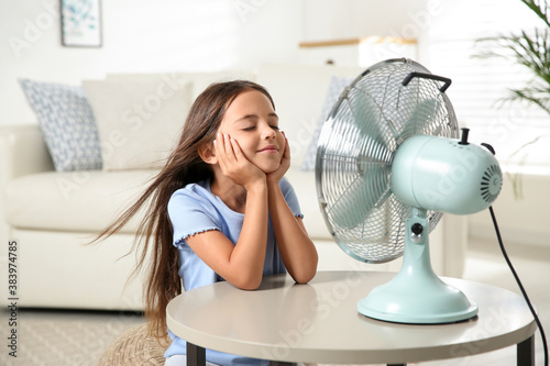 Obraz na plátně Little girl enjoying air flow from fan at home. Summer heat