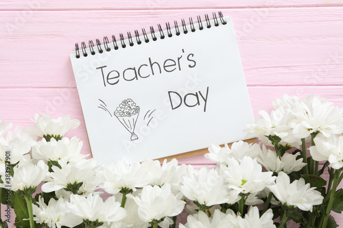 Beautiful flowers and notebook with words TEACHER'S DAY on pink wooden background, flat lay