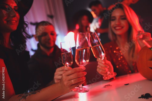 Group of friends toasting with champagne at Halloween party indoors