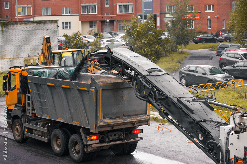 The removed asphalt is poured into the body of the dump truck