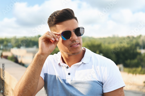 Handsome man wearing stylish sunglasses on city street