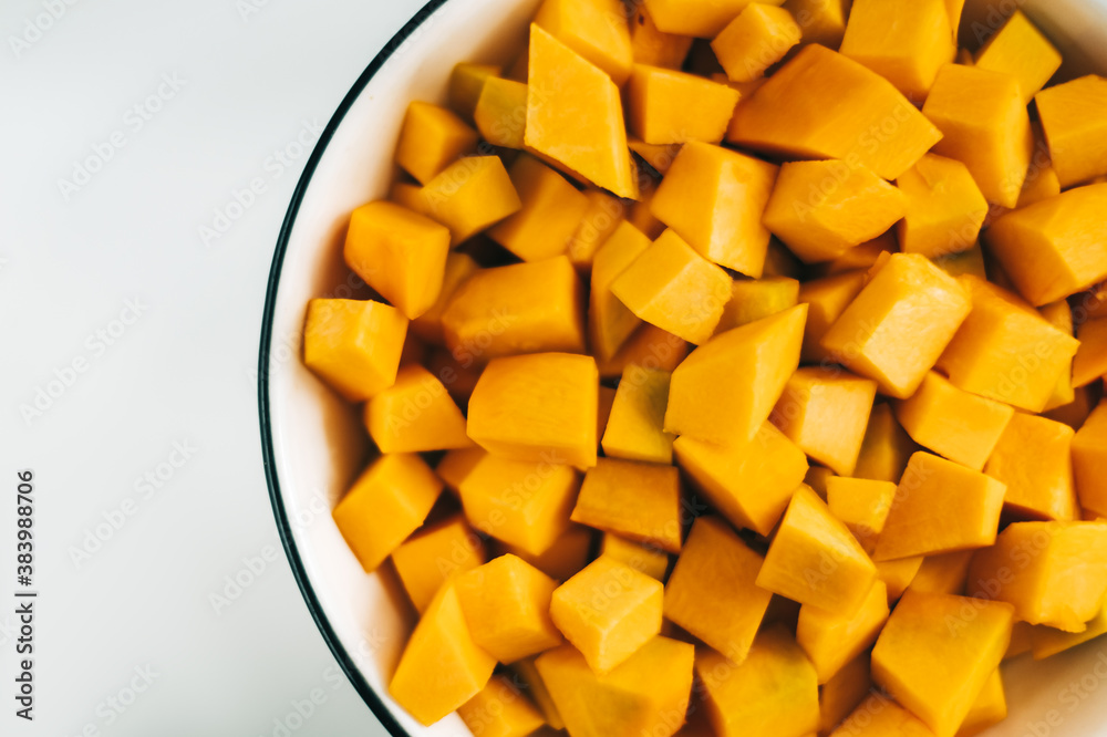 Close up view of fresh, vivid orange pumpkin pieces in a white plate. Healthy and nutritious food.