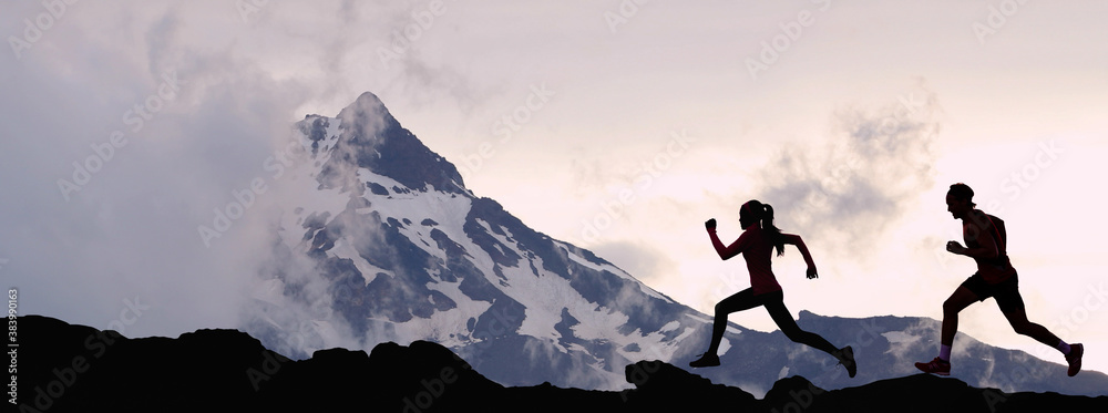 Fototapeta premium Panoramic banner of running people athletes sport fitness concept. Silhouette trail running in mountain summit background. Man and woman on run training outdoors active fit lifestyle.