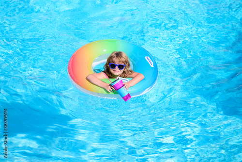 Happy kid playing with colorful swim ring in swimming pool on summer day. Child water toys. Children play in tropical resort. Family beach vacation.