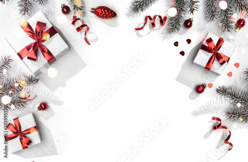 Merry Christmas card made of fir branches, gift boxes, red decoration, sparkles and confetti on white background. Xmas and New Year holiday, bokeh, light. Flat lay, top view