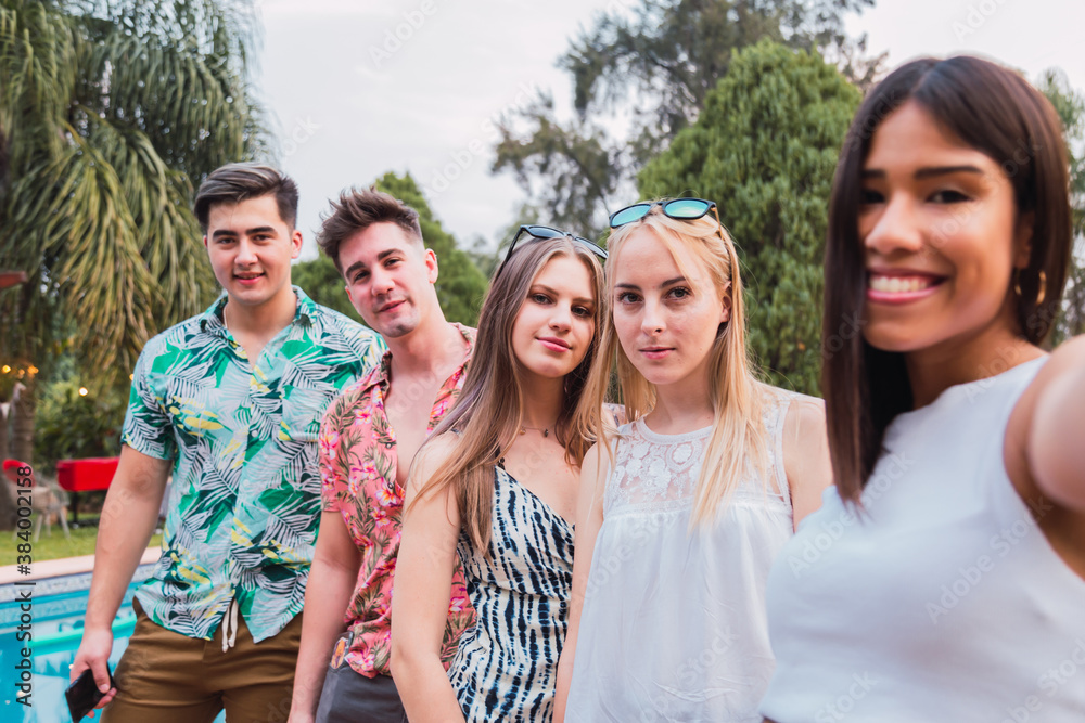 Friends take a portrait in the pool. Millennial group of friends enjoying a day of barbecue. Concept of summer and millennial people.