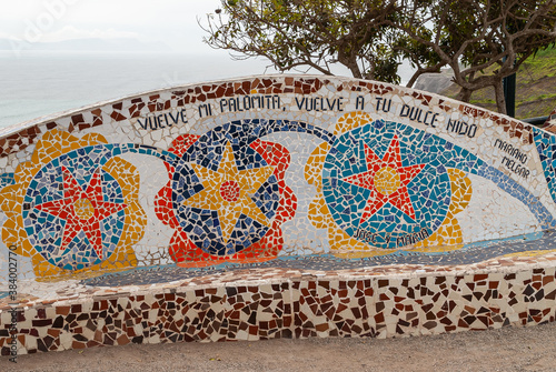 Miraflores, Peru - December 4, 2008: Parque del Amor, Love Park. Artful bench decorated with colorful faience pieces with green foliage over and part of ocean visible. Mariano Melgar poem. photo