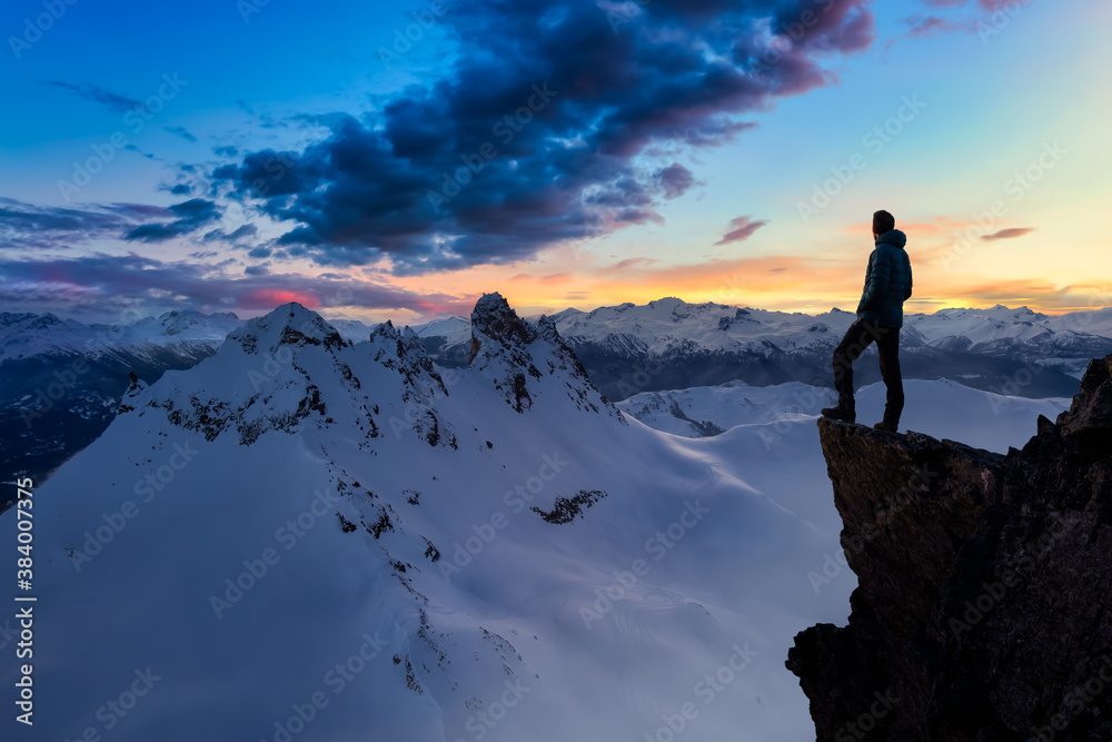 Fantasy Adventure Composite with a Man on top of a Mountain Cliff with Dramatic Landscape in Background during Sunset. Landscape from British Columbia, Canada.
