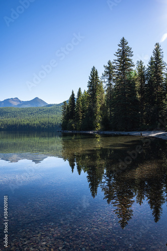 Reflection of Pine Trees in Lake Bowman in Glacier National Park © Justin Mueller