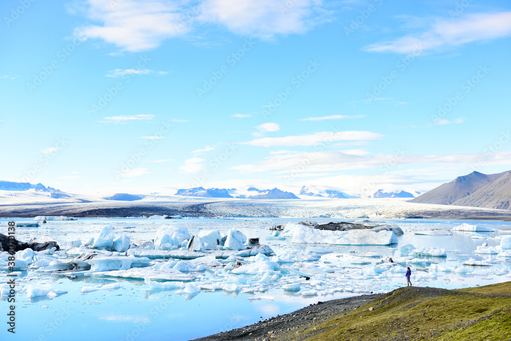 Fototapeta premium Iceland travel tourist enjoying view of nature landscape Jokulsarlon glacial lagoon / glacer lake on Iceland. Woman outdoors by tourist destination landmark attraction. Vatnajokull National Park.