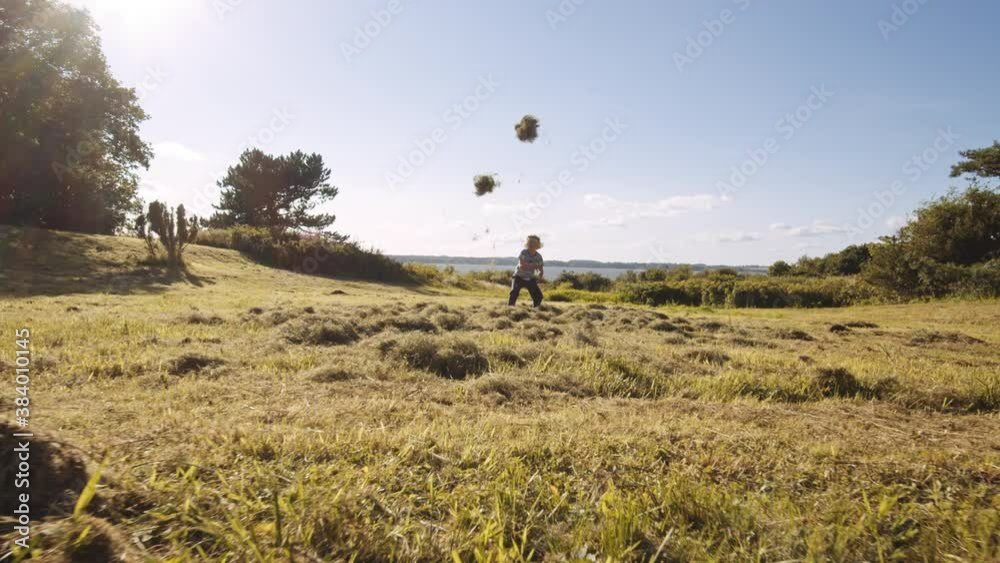 Boy Playing By Throwing Grass In Meadow Boy Playing By Throwing Grass In Meadow