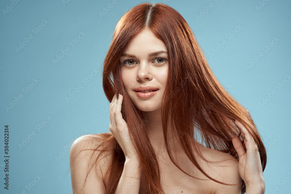 Naklejka premium Pretty woman holding hair in hands grooming naked shoulders cropped view blue background