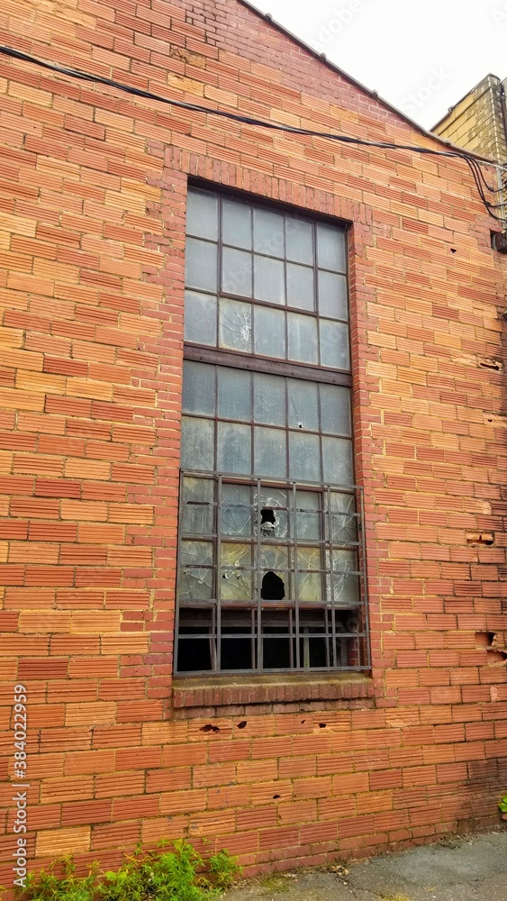 Window of old brick warehouse with broken pains.