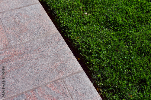 Pink granite walkway with grass creates an abstract composition.
