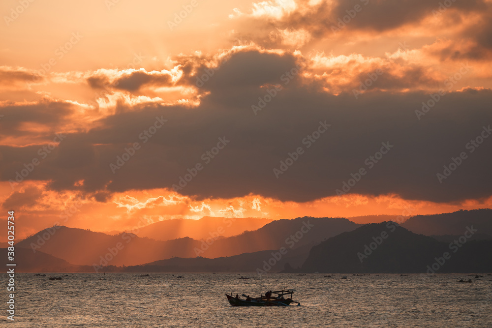 Lonely boat in the ocean by unset with mountains in the horizon. Sunset Over Lombok Island, Indonesia