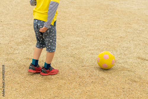 黄色いサッカーボールを蹴ろうとしている子供。 Child's hand holding a yellow soccer ball. photo