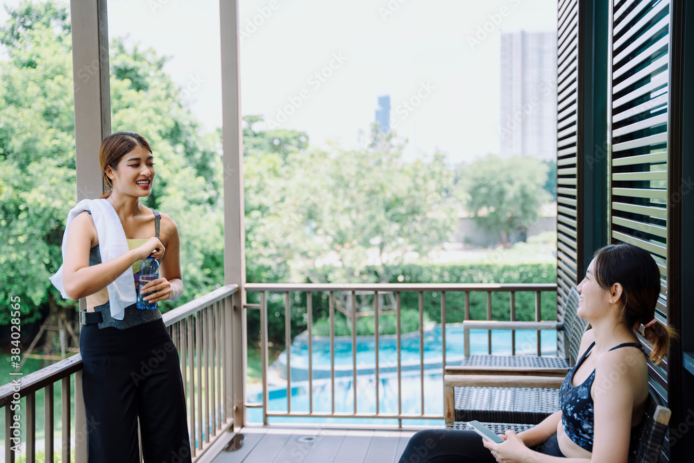 Fototapeta premium Beautiful women talking with friend at balcony after exercising together.