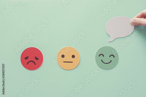 Hand holding speech bubble on happy smile face paper cut, good feedback rating and positive customer review, experience, satisfaction survey ,mental health assessment concept