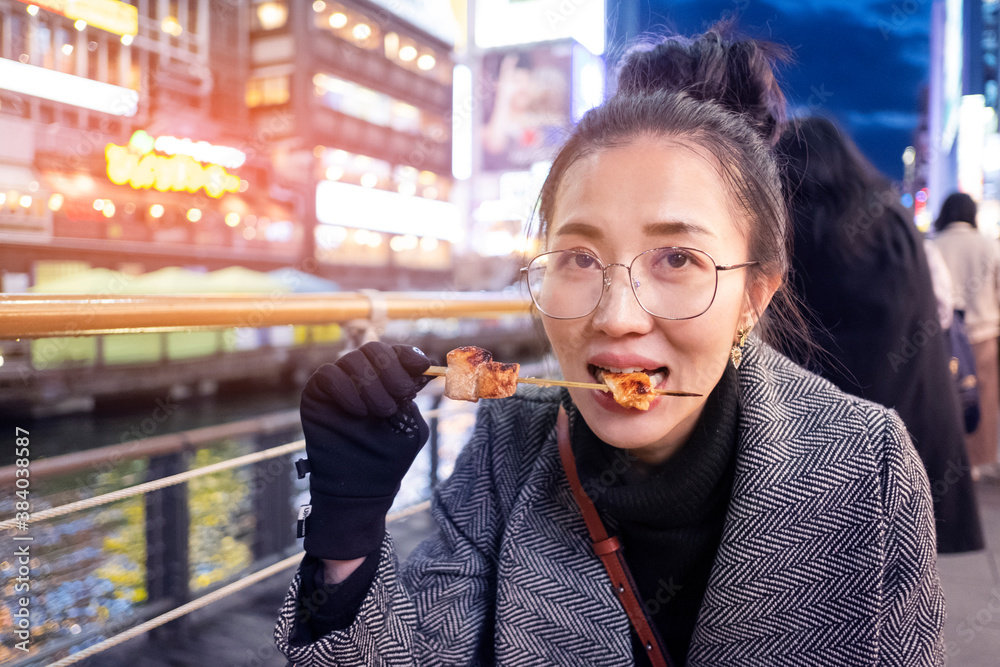Φωτογραφία Young woman tourists enjoy eating street food in walking at street shopping center Dotonbori in Osaka, Japan