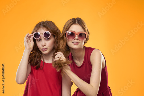 Happy sisters in red dresses on a yellow background are having fun and gesticulating Copy Space