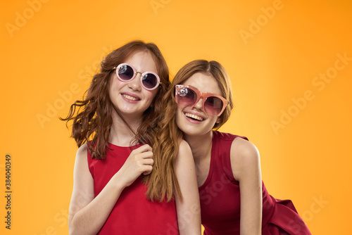 Happy woman and little girl in red dress are having fun on a yellow background fashion emotions sisters fun Copy Space. © SHOTPRIME STUDIO