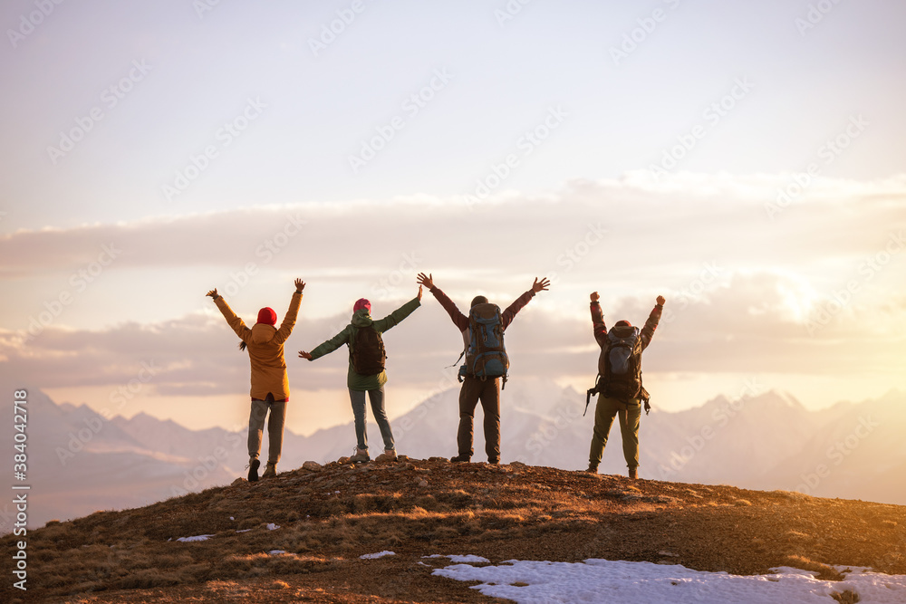 Four tourists stands at mountain top at sunset Four tourists stands at mountain top at sunset