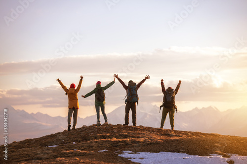 Four tourists stands at mountain top at sunset