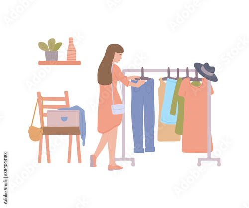 Woman at fashion thrift shop choosing second hand clothes from rack.