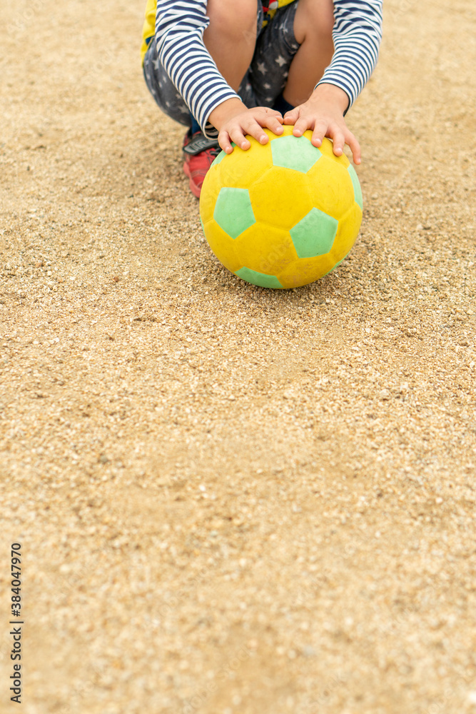 Naklejka premium 黄色いサッカーボールを持つ幼児